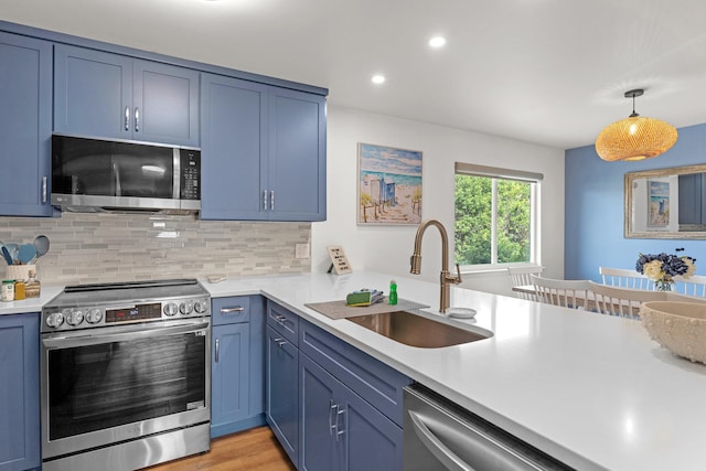 kitchen featuring stainless steel appliances, tasteful backsplash, sink, pendant lighting, and light wood-type flooring