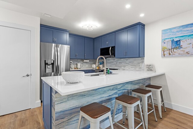 kitchen with a kitchen bar, light hardwood / wood-style floors, appliances with stainless steel finishes, and blue cabinets