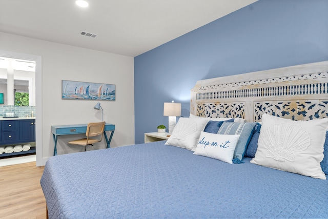 bedroom with ensuite bathroom and light wood-type flooring