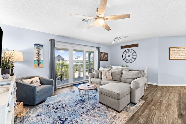 living room featuring rail lighting, a textured ceiling, dark wood-type flooring, and ceiling fan