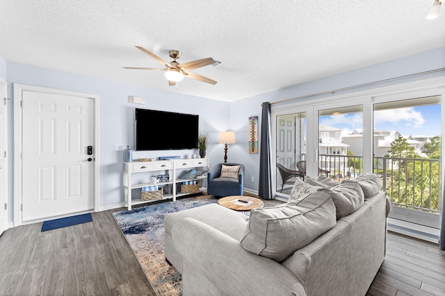 living room with a baseboard heating unit, wood-type flooring, ceiling fan, and a textured ceiling