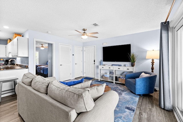 living room featuring sink, ceiling fan, hardwood / wood-style flooring, and a textured ceiling