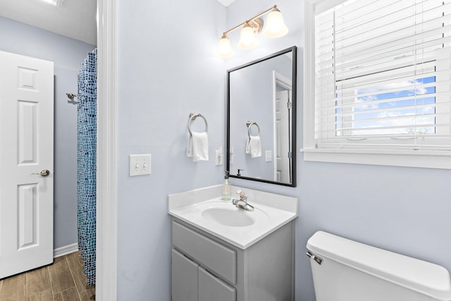 bathroom with wood-type flooring, oversized vanity, and toilet