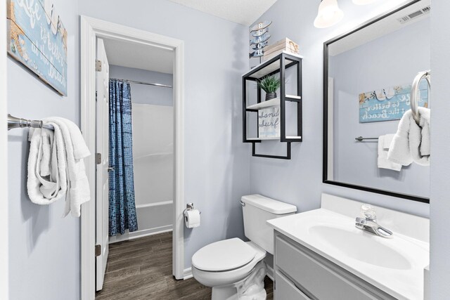 full bathroom featuring toilet, oversized vanity, shower / bath combo with shower curtain, and hardwood / wood-style floors