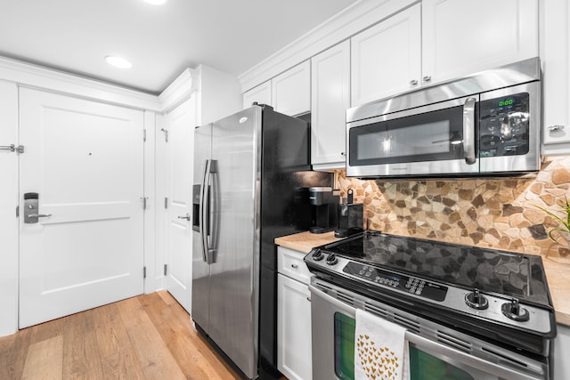 kitchen featuring appliances with stainless steel finishes, white cabinetry, light wood-type flooring, and backsplash