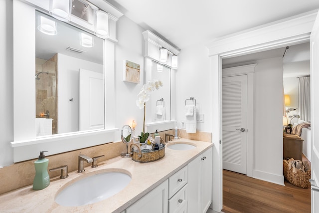 bathroom featuring vanity, tiled shower, and wood-type flooring