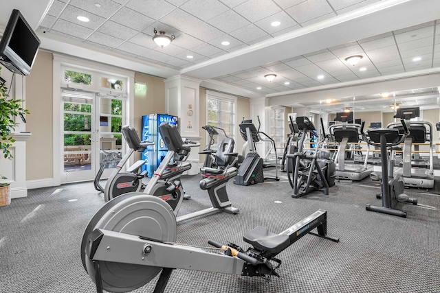 exercise room with a paneled ceiling, crown molding, a raised ceiling, and carpet floors