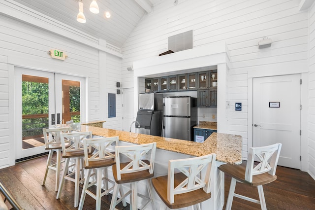 kitchen with beam ceiling, a kitchen bar, french doors, dark hardwood / wood-style floors, and stainless steel refrigerator