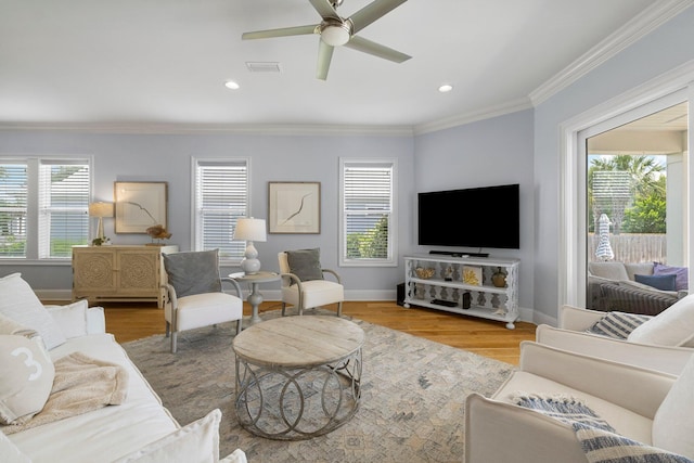 living room featuring wood-type flooring, a wealth of natural light, ceiling fan, and crown molding