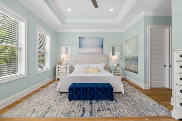 bedroom featuring wood-type flooring, ceiling fan, crown molding, and a raised ceiling