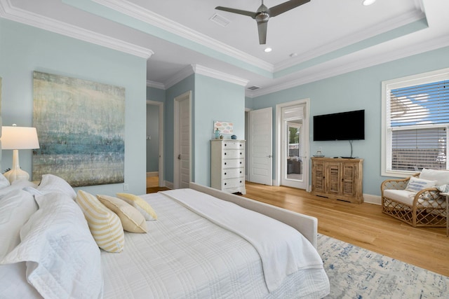 bedroom with wood-type flooring, ceiling fan, a raised ceiling, and multiple windows