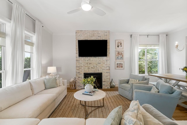 living room with plenty of natural light, hardwood / wood-style floors, crown molding, and a brick fireplace