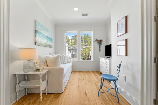 living area featuring crown molding and light hardwood / wood-style floors