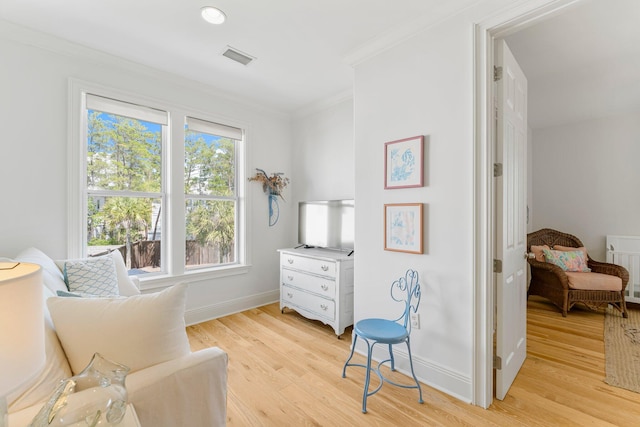 living area with ornamental molding and light wood-type flooring