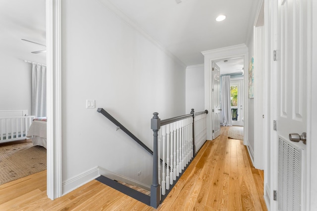 staircase with ornamental molding and light wood-type flooring