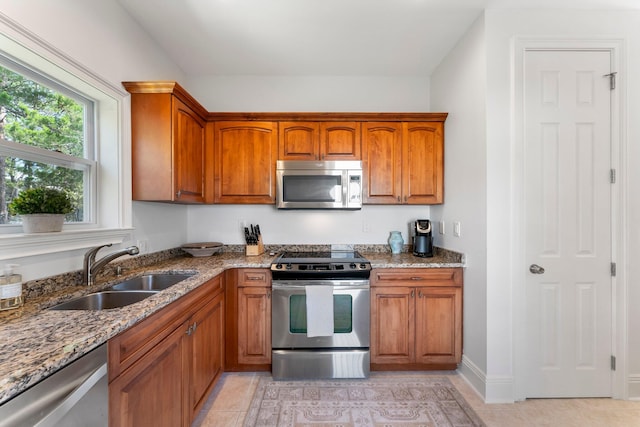 kitchen featuring sink, appliances with stainless steel finishes, light tile flooring, and light stone counters