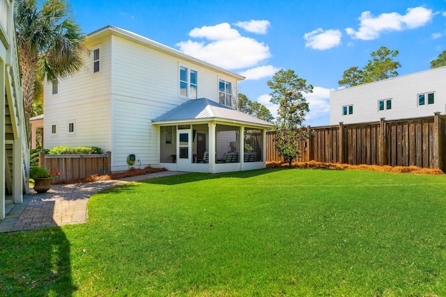 rear view of house featuring a yard and a sunroom