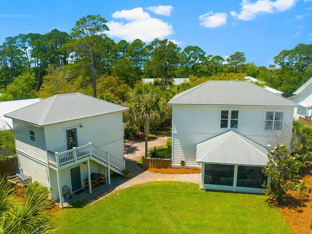 back of house with a wooden deck, a sunroom, and a lawn