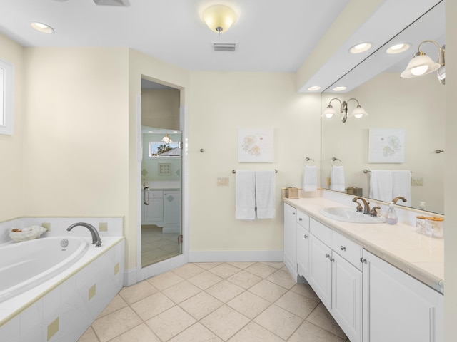 bathroom with tile flooring, vanity, and tiled bath