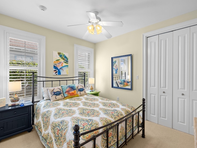 bedroom featuring light colored carpet, a closet, and ceiling fan