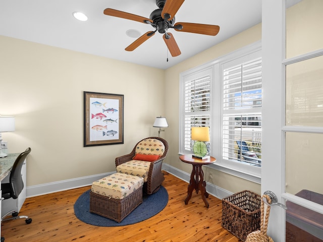 living area featuring a wealth of natural light, wood-type flooring, and ceiling fan