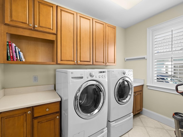 washroom featuring washing machine and clothes dryer, cabinets, and light tile floors