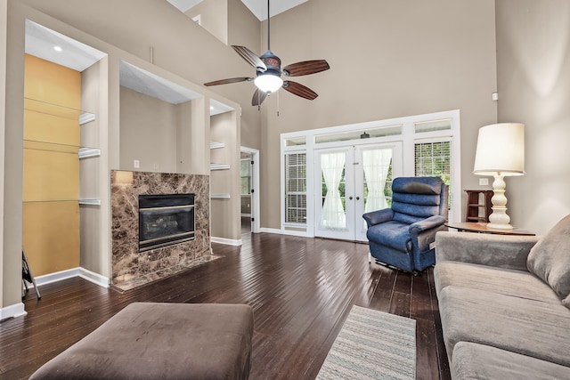 living room with a premium fireplace, a towering ceiling, ceiling fan, and dark hardwood / wood-style floors