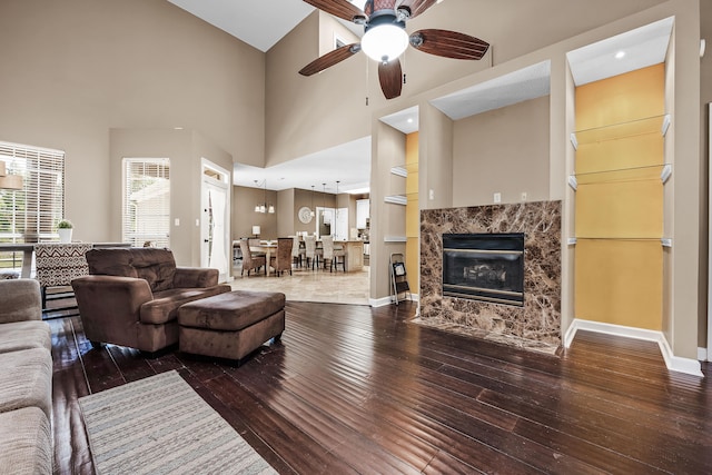 living room featuring a high ceiling, ceiling fan, a high end fireplace, and hardwood / wood-style floors