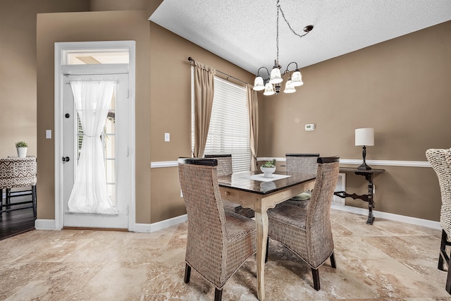 tiled dining area with plenty of natural light, a textured ceiling, and a chandelier