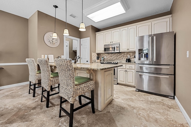 kitchen with stainless steel appliances, a kitchen island with sink, backsplash, pendant lighting, and light tile floors