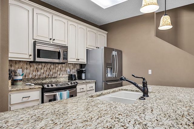 kitchen featuring light stone counters, stainless steel appliances, backsplash, sink, and pendant lighting