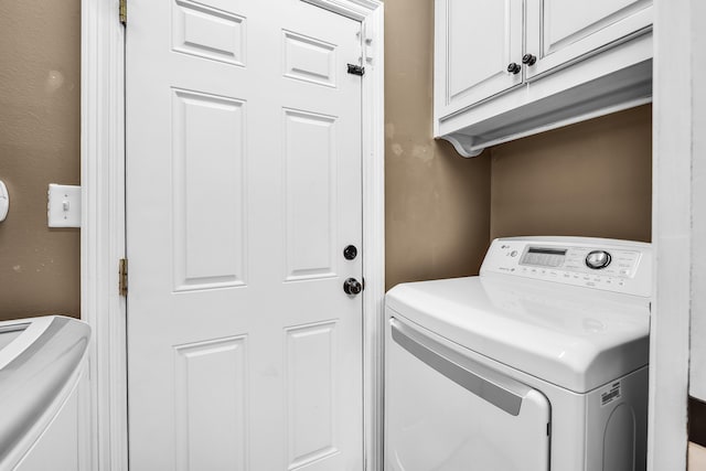 laundry area with washing machine and clothes dryer and cabinets