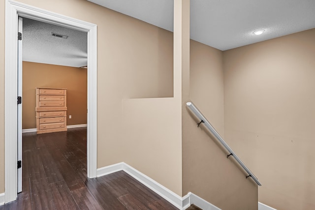 stairs with a textured ceiling and dark hardwood / wood-style floors