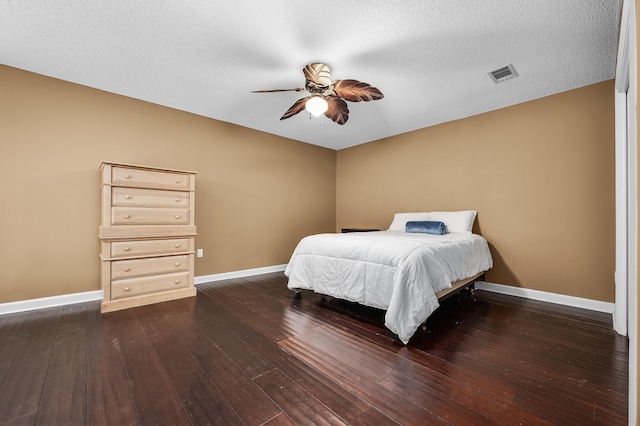 bedroom featuring a textured ceiling, dark wood-type flooring, and ceiling fan