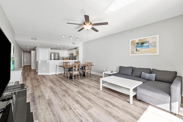 living room with rail lighting, a textured ceiling, ceiling fan, and light wood-type flooring