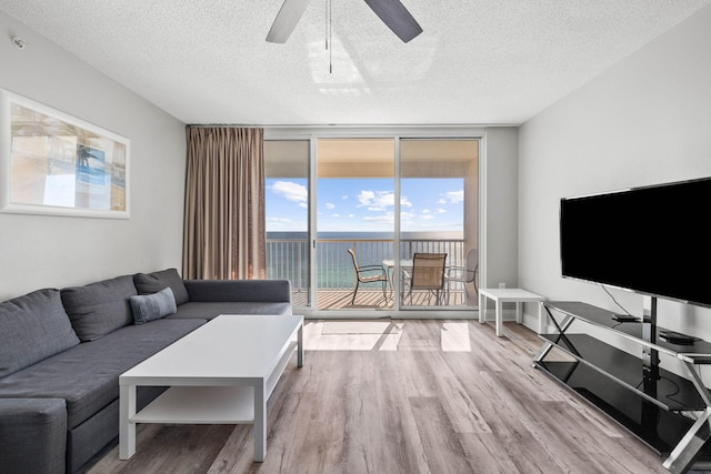 living room with expansive windows, a textured ceiling, ceiling fan, and light wood-type flooring