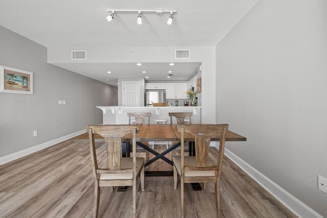 dining space featuring light hardwood / wood-style floors and a textured ceiling