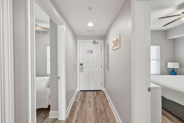 corridor with a textured ceiling and light hardwood / wood-style floors