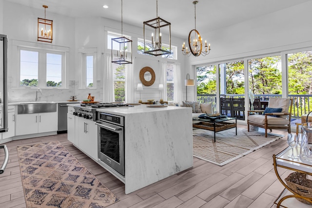 kitchen with sink, tasteful backsplash, light wood-type flooring, white cabinetry, and plenty of natural light