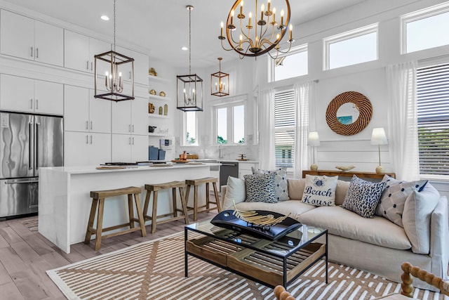 living room with a healthy amount of sunlight, light hardwood / wood-style flooring, and an inviting chandelier