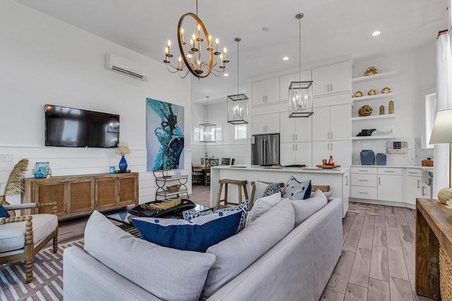 living room featuring a notable chandelier, a wall mounted AC, and light wood-type flooring