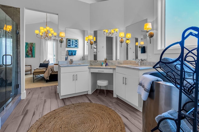 bathroom with a shower with door, hardwood / wood-style floors, vanity, and a notable chandelier