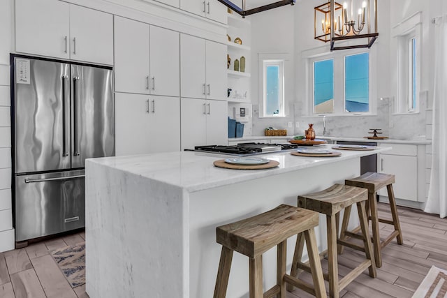 kitchen featuring decorative light fixtures, appliances with stainless steel finishes, light hardwood / wood-style flooring, a center island, and a breakfast bar