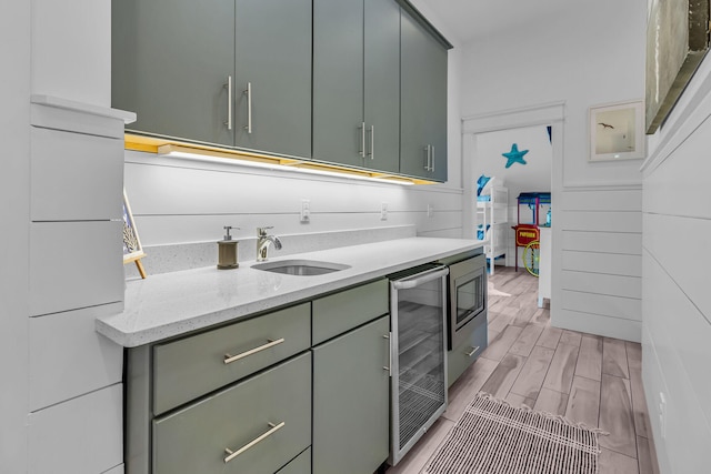 kitchen with wine cooler, light hardwood / wood-style flooring, sink, and light stone countertops