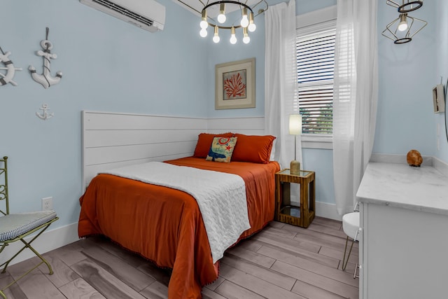 bedroom with a chandelier, light wood-type flooring, and a wall mounted AC