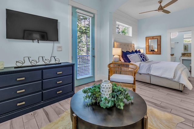 bedroom with ensuite bathroom, light hardwood / wood-style floors, ceiling fan, and access to exterior