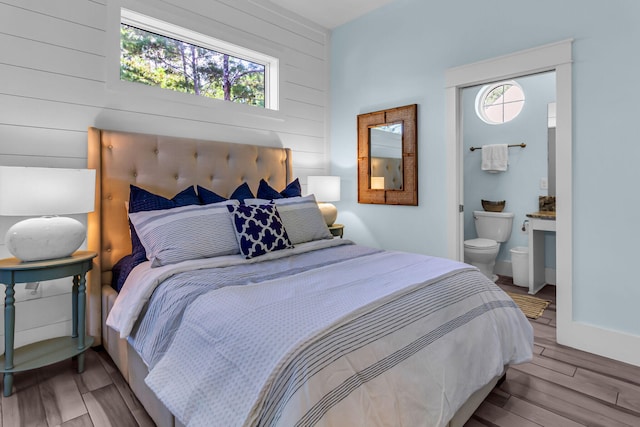 bedroom with hardwood / wood-style floors and ensuite bathroom