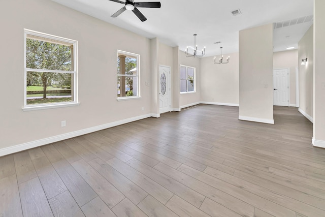 unfurnished room with ceiling fan with notable chandelier and hardwood / wood-style flooring