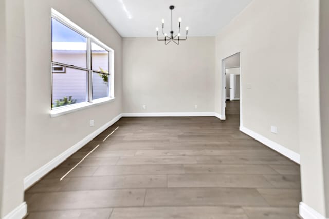 unfurnished room with wood-type flooring and a notable chandelier