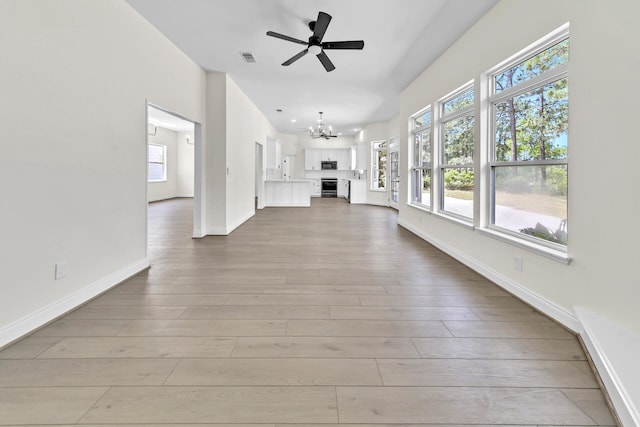 unfurnished living room featuring ceiling fan with notable chandelier and hardwood / wood-style flooring